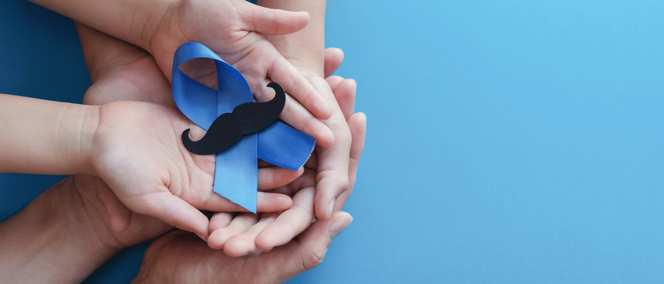 Family hands holding light blue ribbonwith mustache on blue back